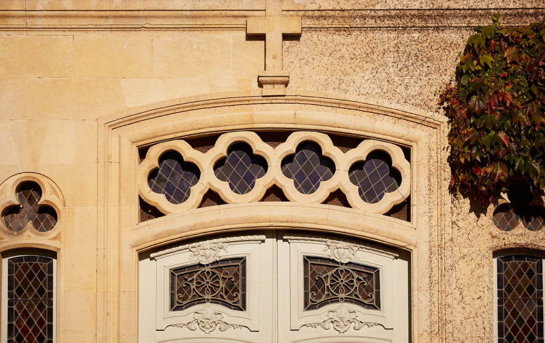 Decorative stone window with intricate designs on a building facade.