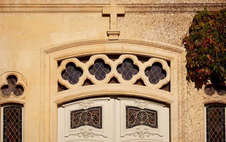 Decorative stone window with intricate designs on a building facade.