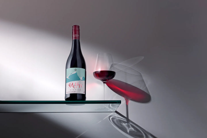 Wine bottle and glass on a reflective surface with a gray background