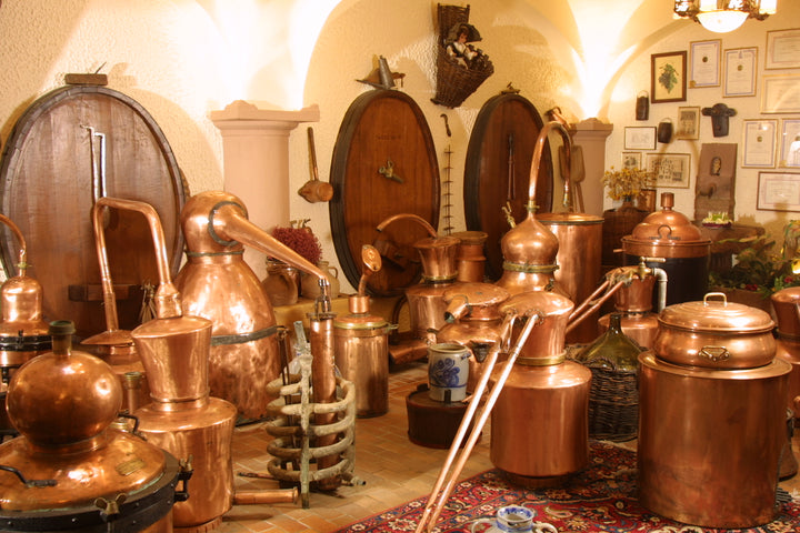 Collection of copper stills and barrels in a rustic setting