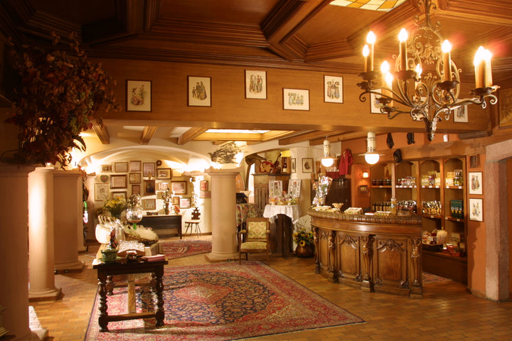 Luxurious interior of a mansion with wooden decor, chandelier, and ornate furniture.